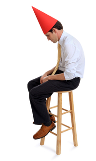 Man with dunce cap on stool
