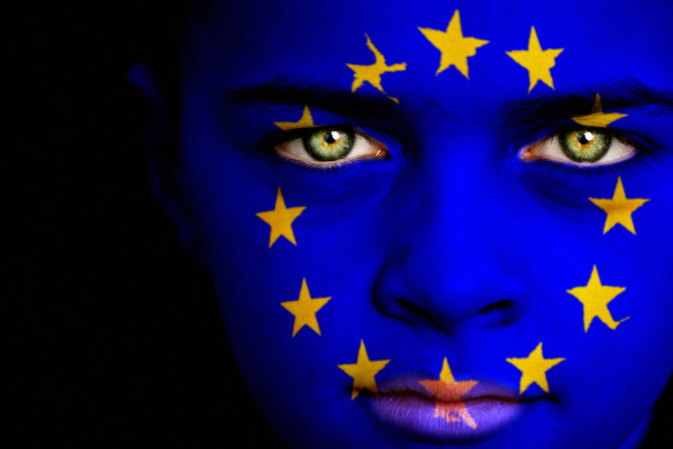 Portrait of a boy with the flag of the European Union painted on his face.