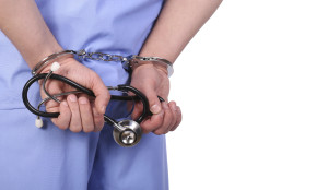 Doctor with stethoscope in handcuffs isolated on white