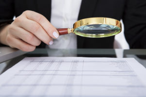 Businesswoman Looking At Document Through Magnifying Glass