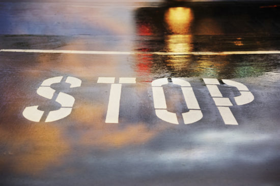Road junction, stop word, motion blurred car in pouring rain