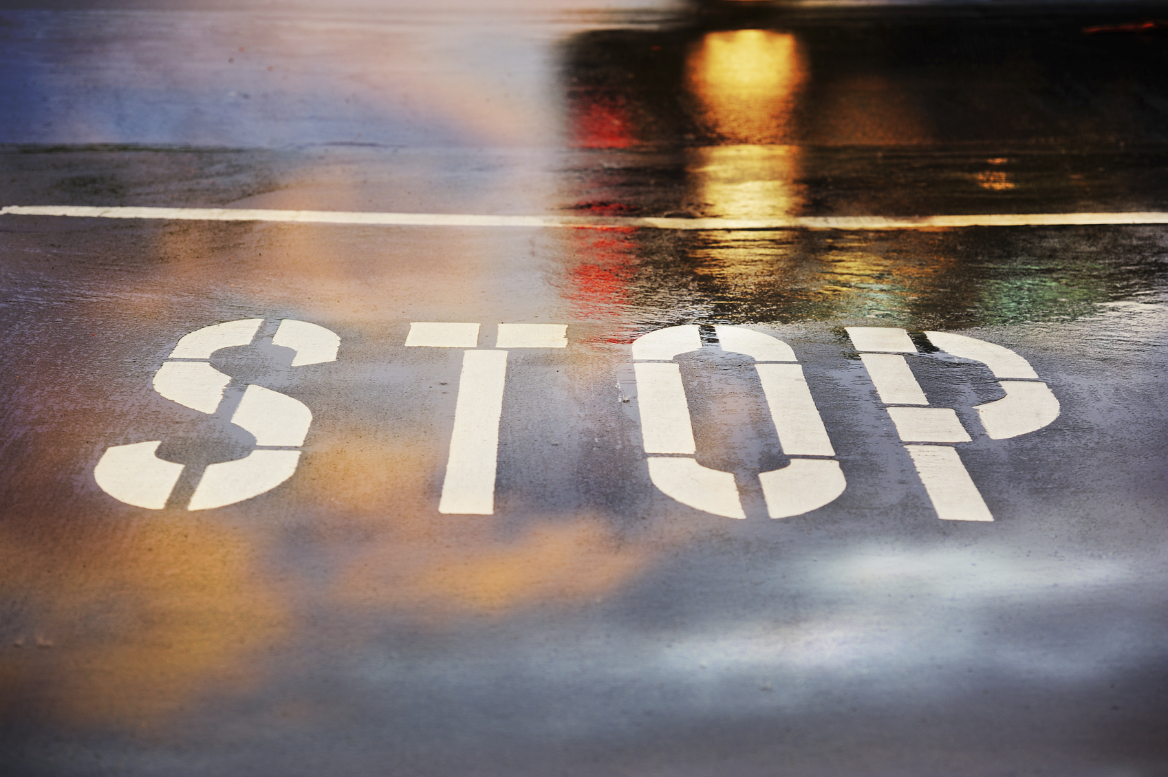 Road junction, stop word, motion blurred car in pouring rain