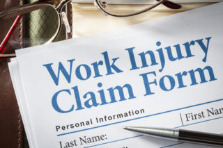 Work Injury Claim Form on desk with glasses and pen