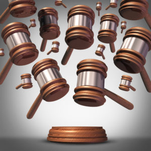 50924014 - class action lawsuit concept as a plaintiff group represented by many judge mallets or gavel icons coming down as a symbol for social litigation or organized legal legislation.