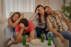 60987399 - four young friends drunk and hungover after house party sitting on the couch.