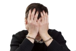 Man in handcuffs covering face