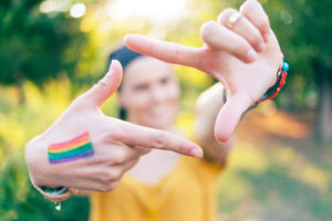 Woman with colored flag on hand making finger frame