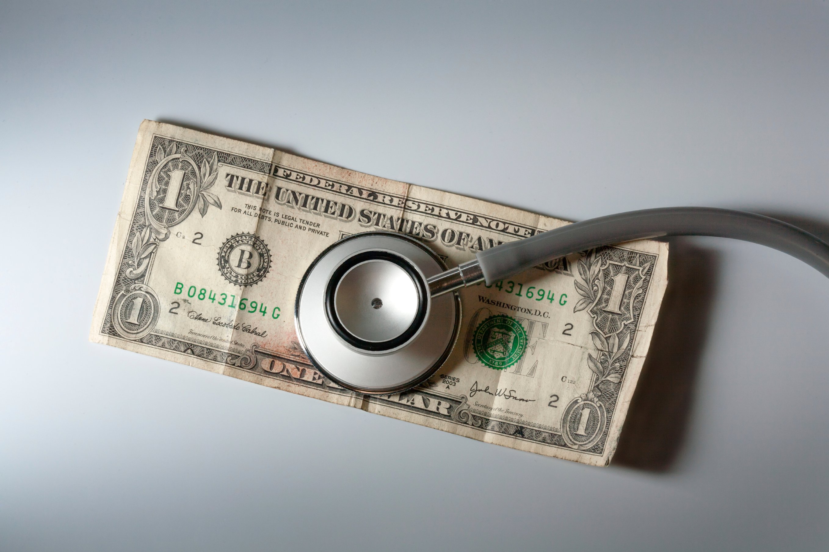 A stethoscope and American money on a white background - Healthc