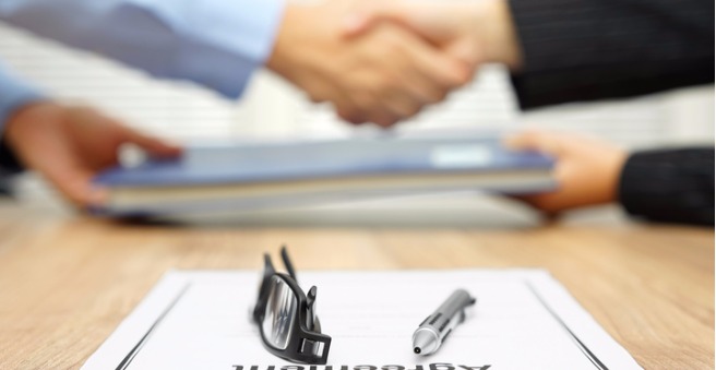 businessman-and-businesswoman-are-shaking-hands-and-exchanging-folder-picture-id512154742