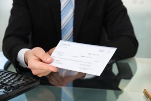 Businessman handing over paycheck at desk in office