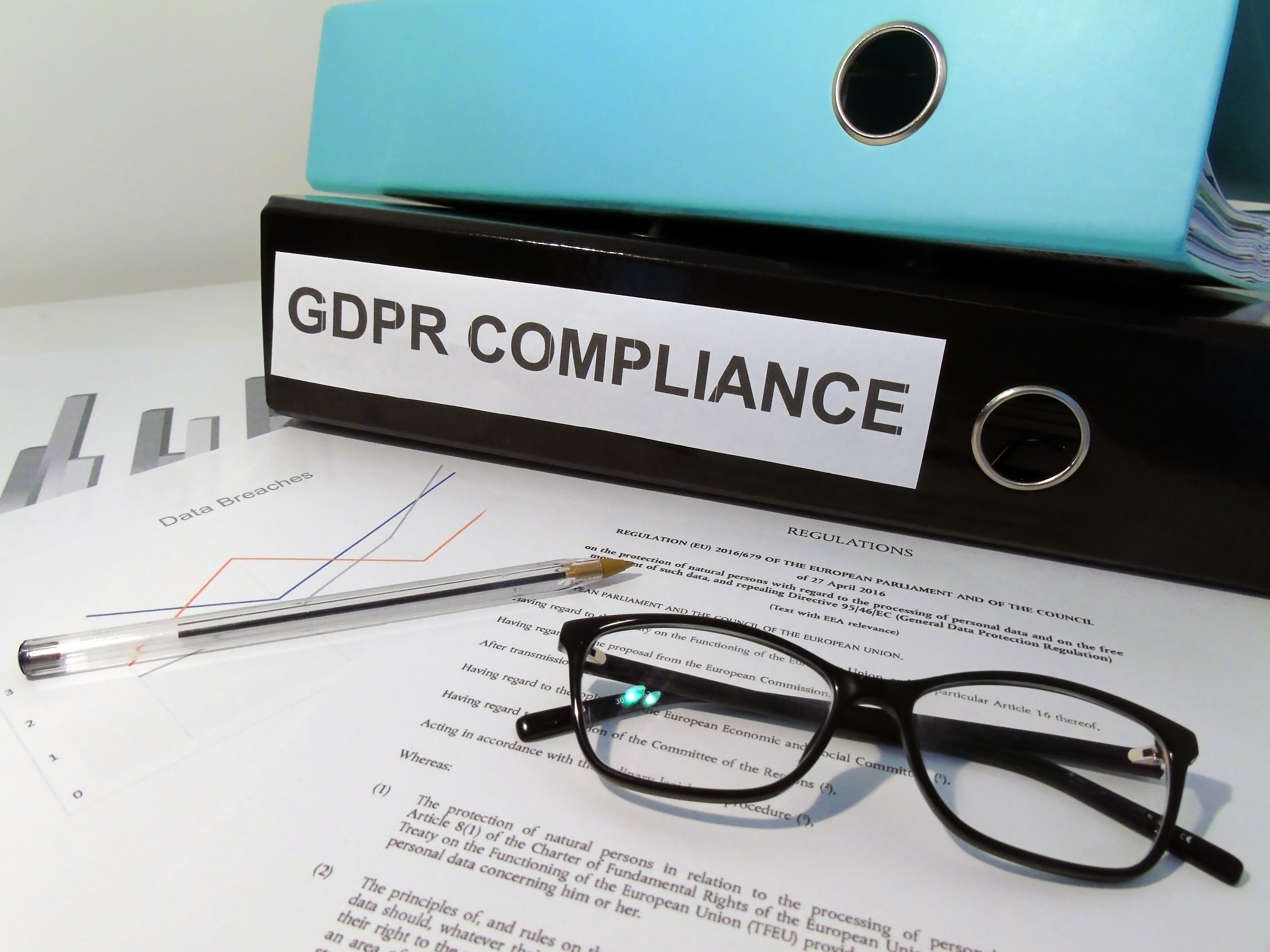 General Data Protection Regulation (GDPR) Compliance Lever Arch Folders on Desk with Documents (Legislative Text and Graphs), Glasses and Pen