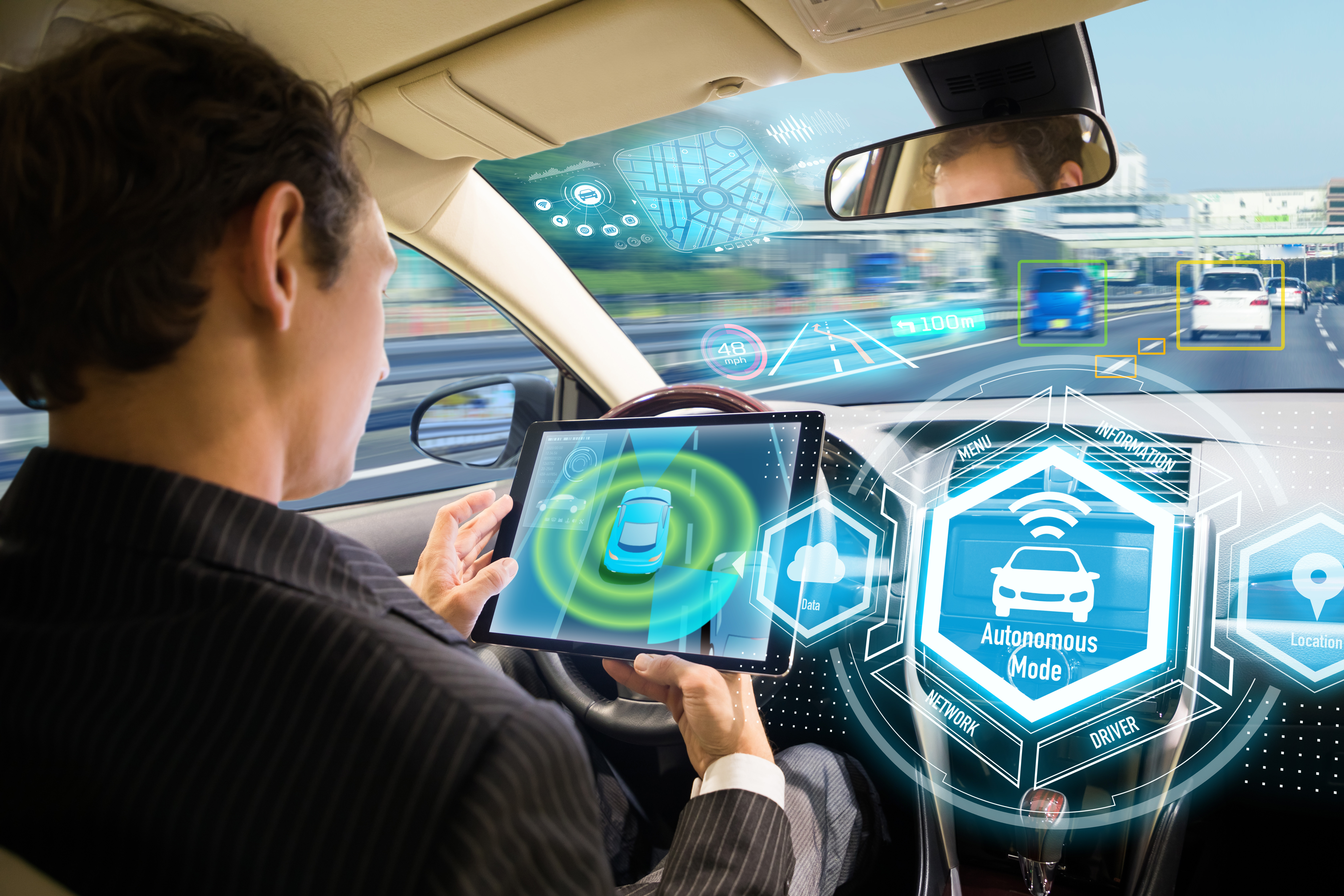 Driverless_car_with_person_in_drivers_seat_looking_at_tablet