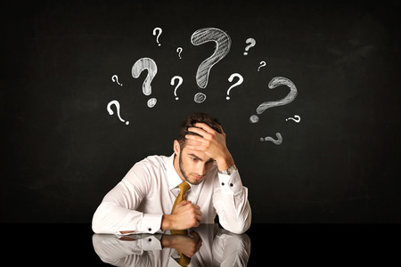 40355395 - depressed businessman sitting under question marks
