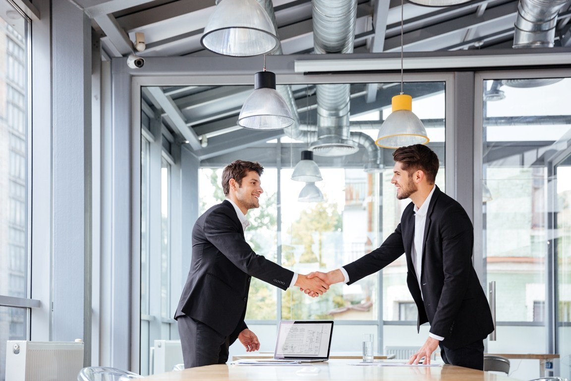 two-happy-businessmen-standing-and-shaking-hands-P5PKEXG.jpg
