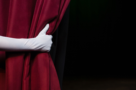 84481492 - close-up of hand in a white glove pulling curtain away