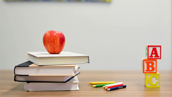 teachers classroom supplies - apple, stack of books, colored pencils and A B C blocks