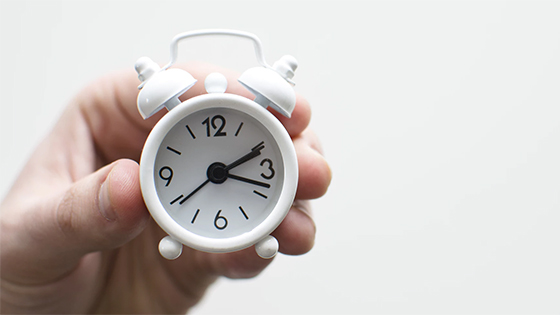 hand holding a clock to represent not wasting time in not-for-profit board meetings