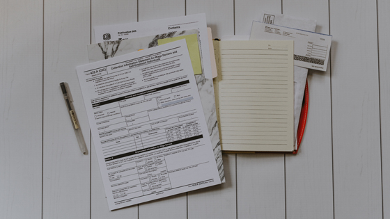A photo of a folder, a journal and a stack of paper to make not-for-profit employees aware of reimbursement plans.
