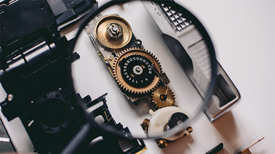a person holding a magnifying glass to closely look at mechanical wedges; image used for a blog post about ERM systems reducing risk for not-for-profits