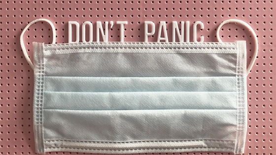 a medical face mask and letters spelling, "Don't Panic," on top of a pink corkboard; image used for blog post about COVID-19 Tax Relief for Individuals