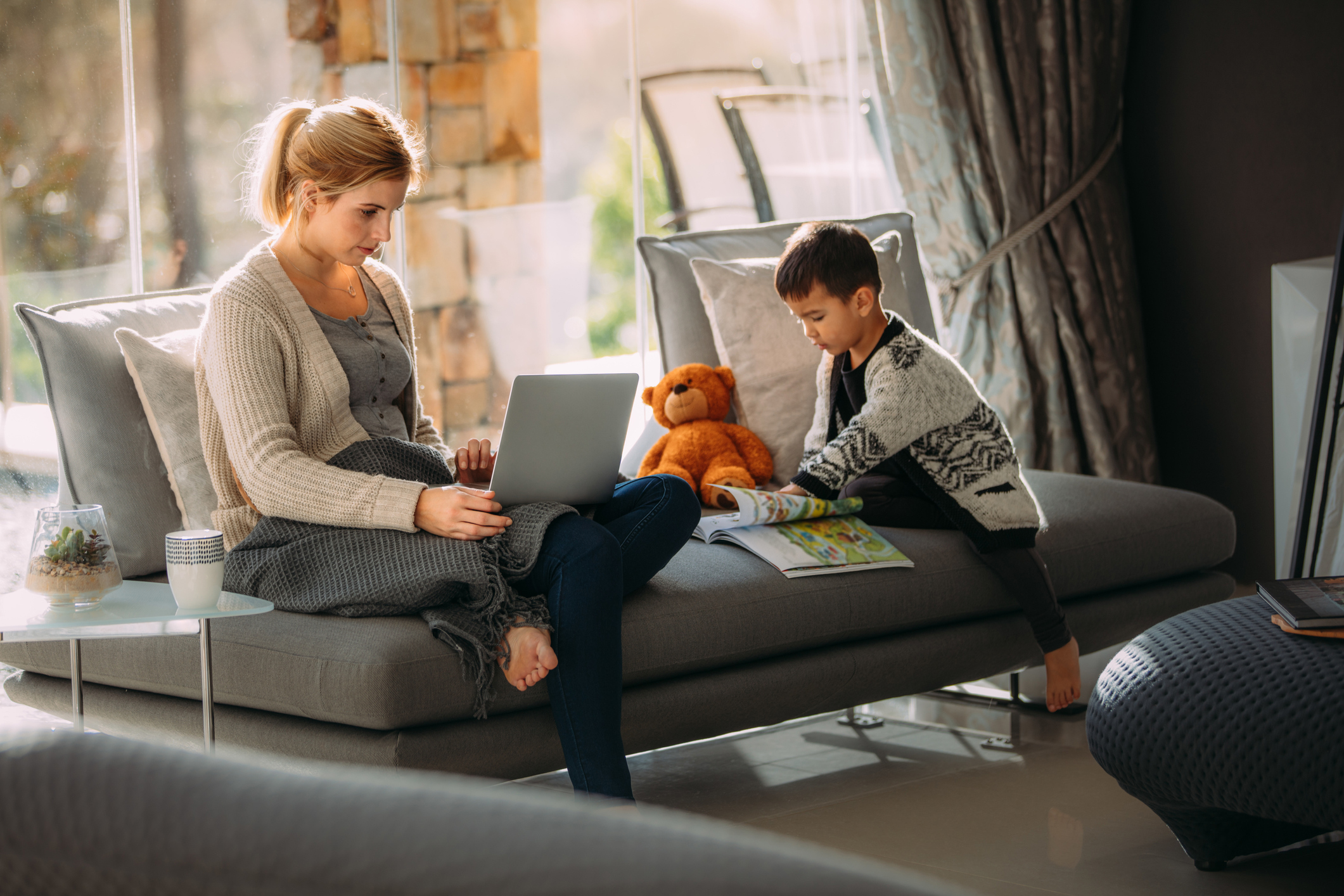 Mother working on laptop and son reading story book