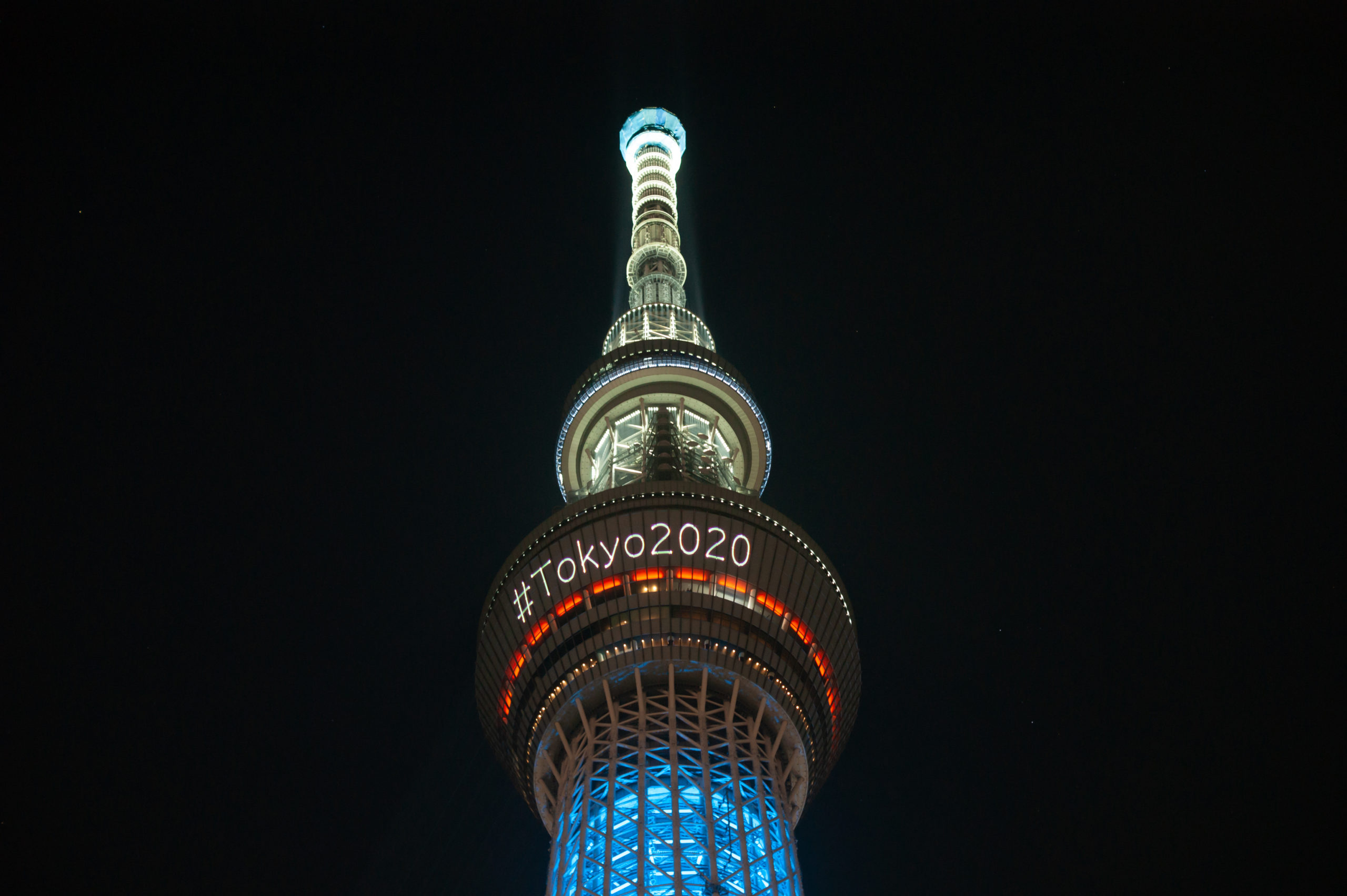The skytree tower is illuminated at night announcing the olympics of Tokyo 2020 with a hashtag.