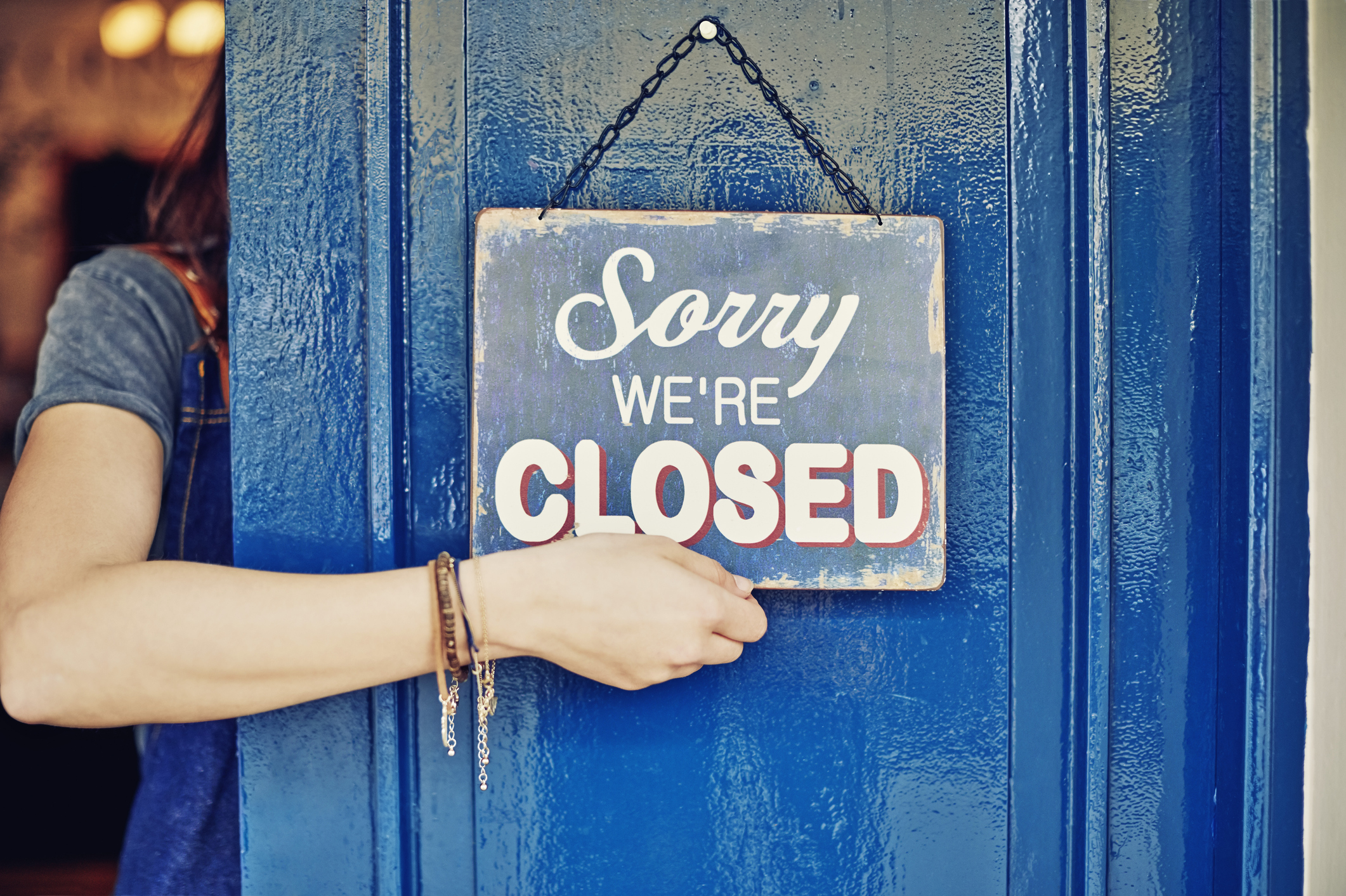 Female deli entrepreneur hanging closed sign from behind door