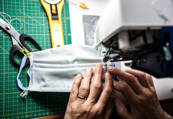 high-angle-view-closeup-of-mature-woman-sewing-protective-face-masks-picture-id1215739262