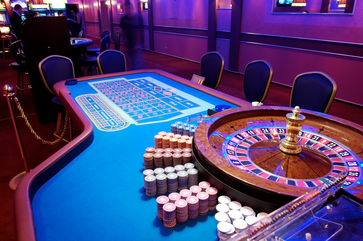 Empty casino roulette table with chairs and chips