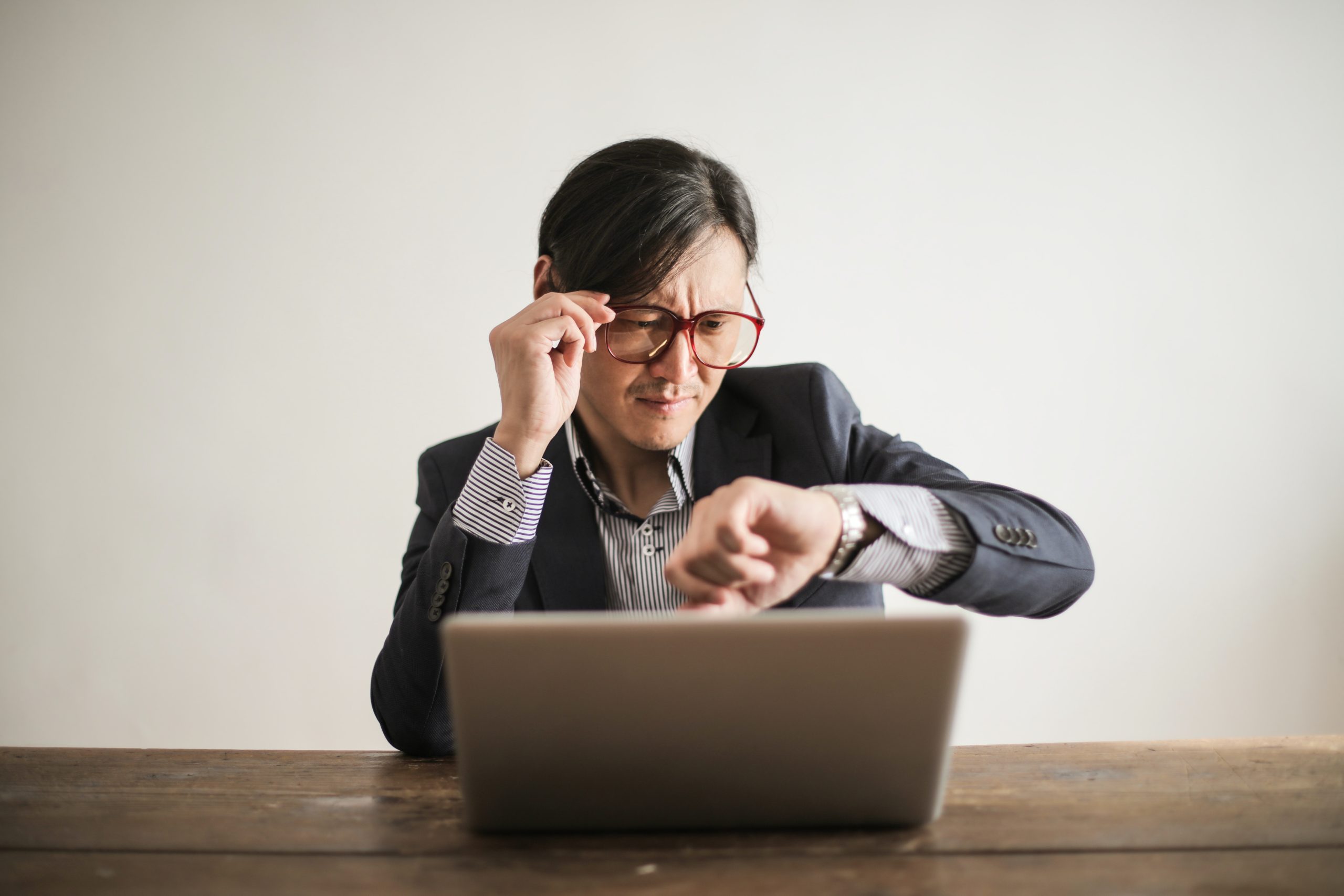 confused-businessman-checking-time-on-wristwatch-3760810