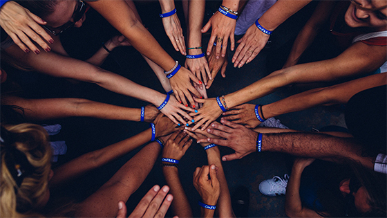 a diverse group of hands reaching together in the center as a sign of teamwork; image used for blog post about how not-for-profits can appeal to Gen Z