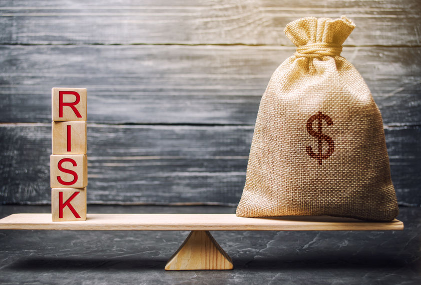 Money bag and wooden blocks with the word Risk. The concept of financial risk. Justified risks. Investing in a business project. Making the right decision. Property insurance. Legal and market risks