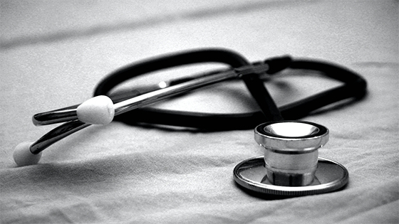 black and white photo of a doctor's stethoscope lying on a blanket sheet; image used for a blog post about tax implications of life insurance provided by employers