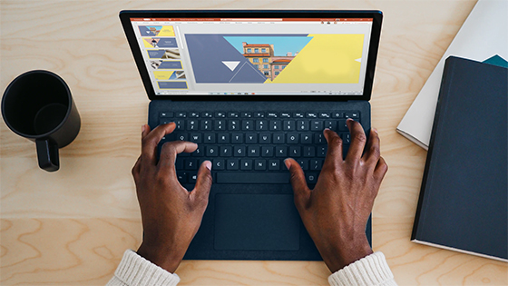 Black man working on a laptop at home on a wooden desk; image used for blog post about working from home and collecting unemployment tax implications