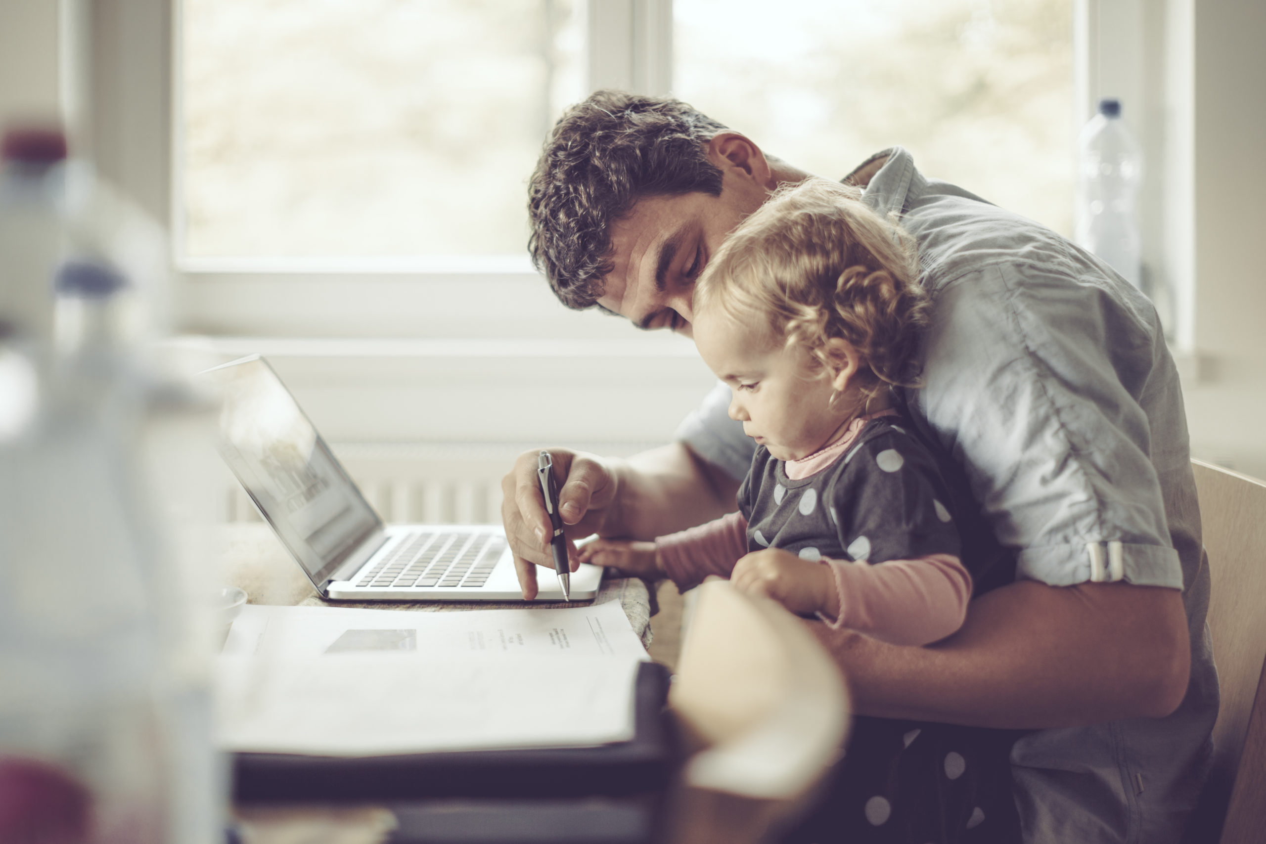 Fahter is showing his daughter things on a laptop