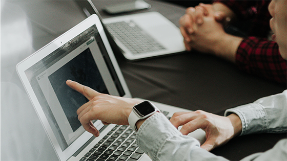 man pointing to a laptop screen showing a client what's on the screen; image used for blog post about not-for-profit insurance as part of a risk management plan