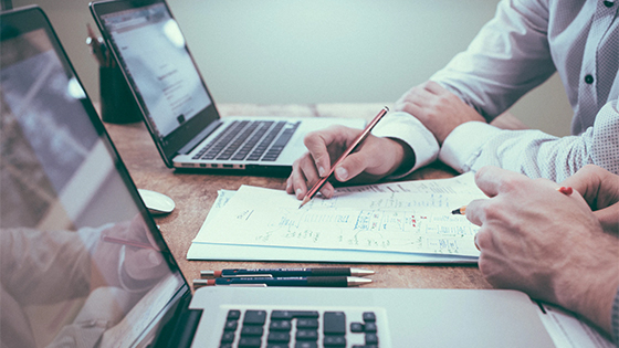 two businessmen writing on a document together; image used for blog post about using footnotes in a not-for-profit's financials