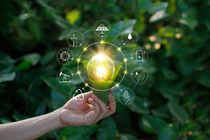 Hand holding light bulb against nature on green leaf with icons energy sources for renewable, sustainable development. Ecology concept. Elements of this image furnished by NASA.