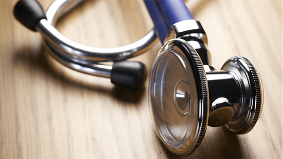 a blue doctor's stethoscope sits on a wooden table; image used for blog post about medical expenses tax deduction