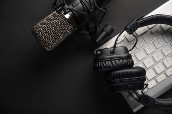 Flat lay, Studio microphone with professional headphones on a PC keyboard. Black on a black background. Podcasts, radio, streams, blogging, working with sound, recording tracks