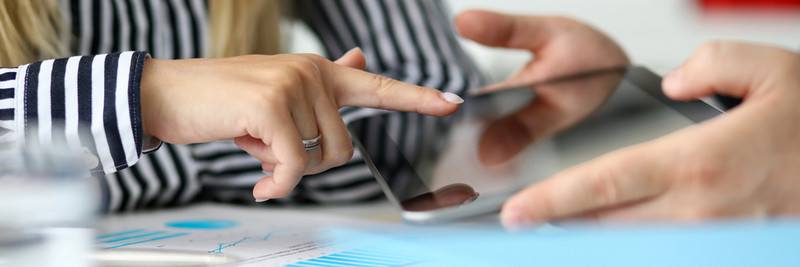 Man offering female client tablet PC to confirm deal using digital signature