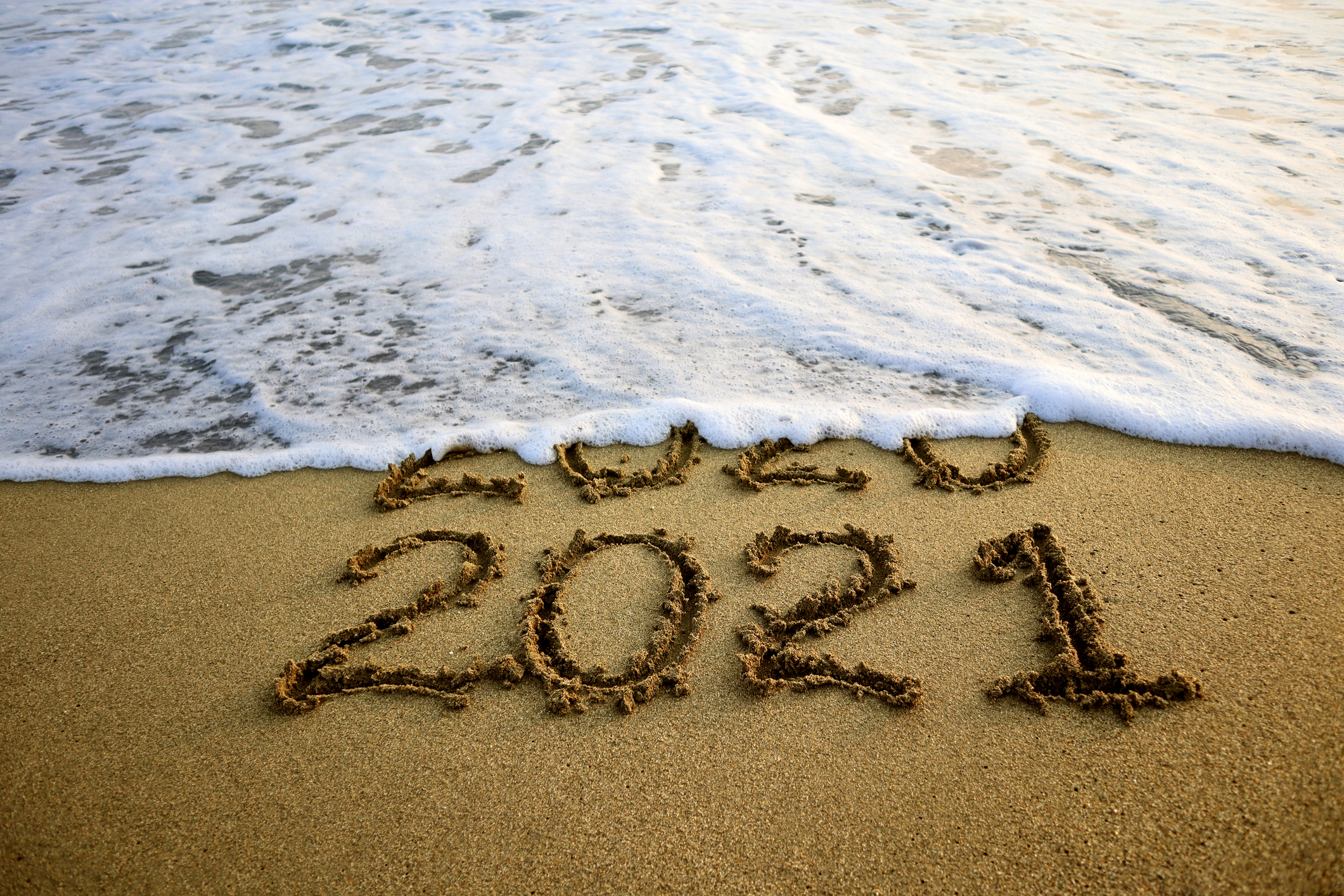 New year 2021 and 2020 on sandy beach with waves
