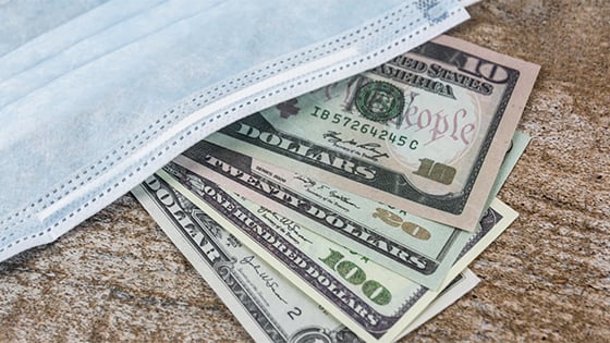 hundred dollar bills underneath a health mask; image used for blog post about direct payments from American Rescue Plan Act of 2021