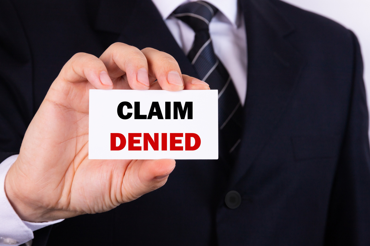 Businessman holding a card with text Claim Denied