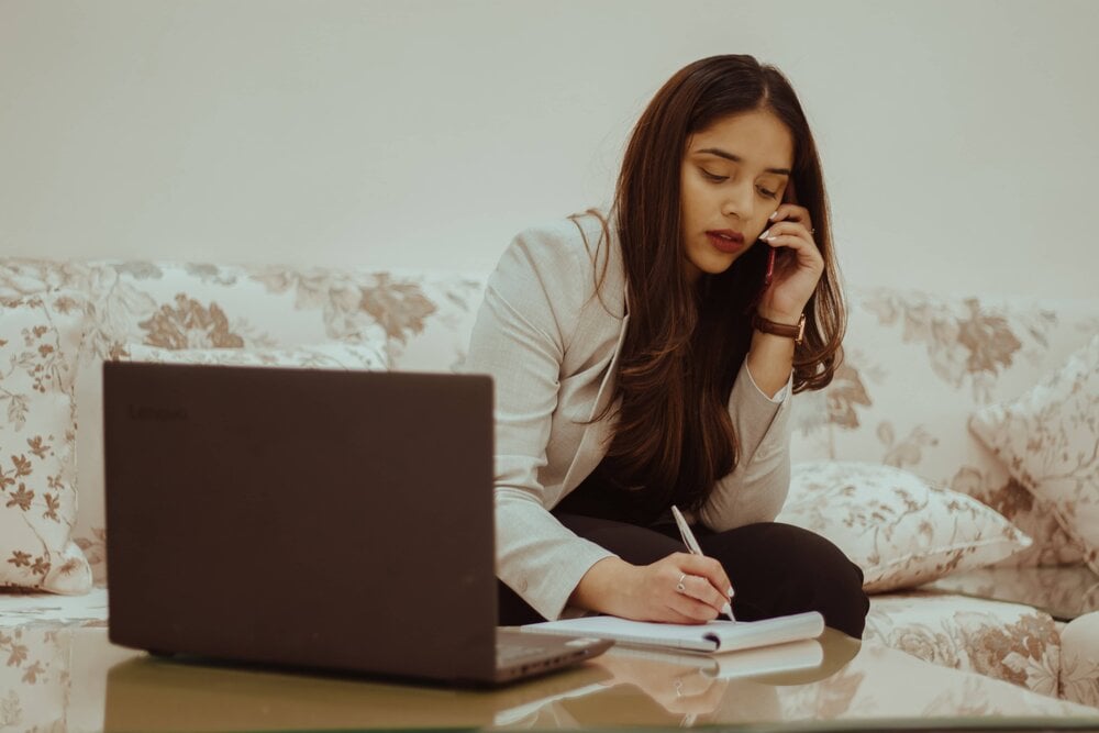 woman talking on the phone while working on laptop.jpg