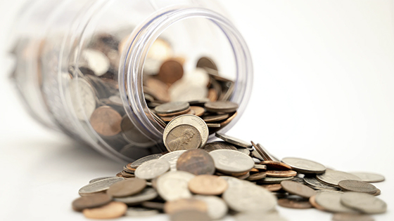coins spilling out of a clear glass jar; image used for blog post about 4 tax issues you may face when retiring soon