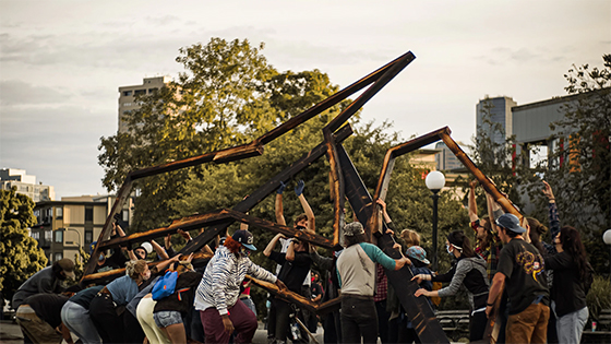 a group of people in masks holding up a wooden structure; image used for blog post about tackling volunteer liability