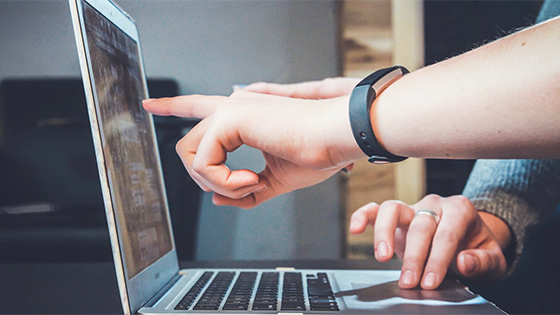 person pointing at a laptop screen with another person; image used for blog post about not-for-profit's sponsorships and advertising being taxable