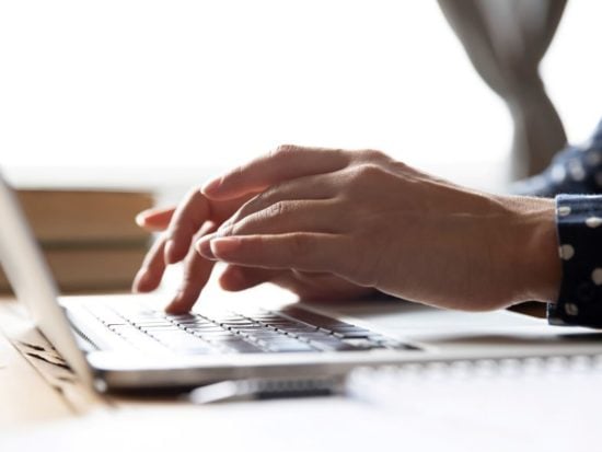 Woman's hands working on laptop - web- iStock-1198252560