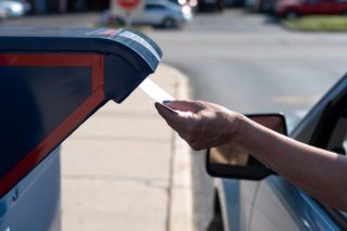 Safely mailing an application for ballot for 2020 election at a  drive-up mailbox at the US Post Office